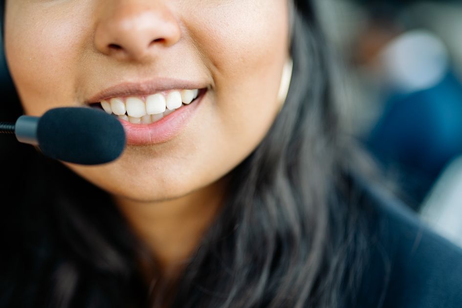 A customer service agent smiling while wearing a headset
