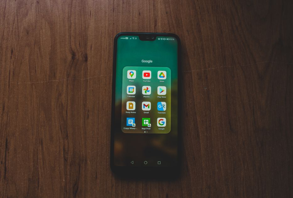 A smartphone showcasing various apps on a wooden table