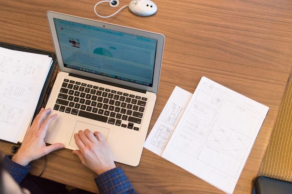 An overhead view of a person working on a laptop with documents