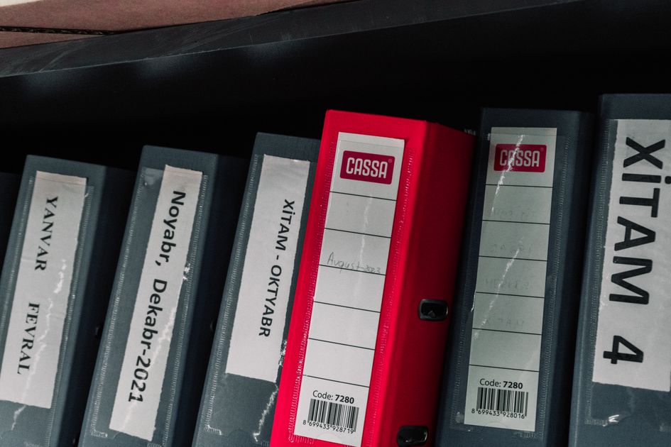 Color-coded office binders organized on a storage shelf