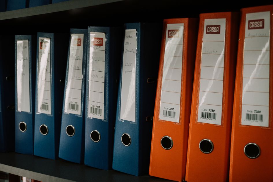 A row of colorful office binders arranged on a shelf