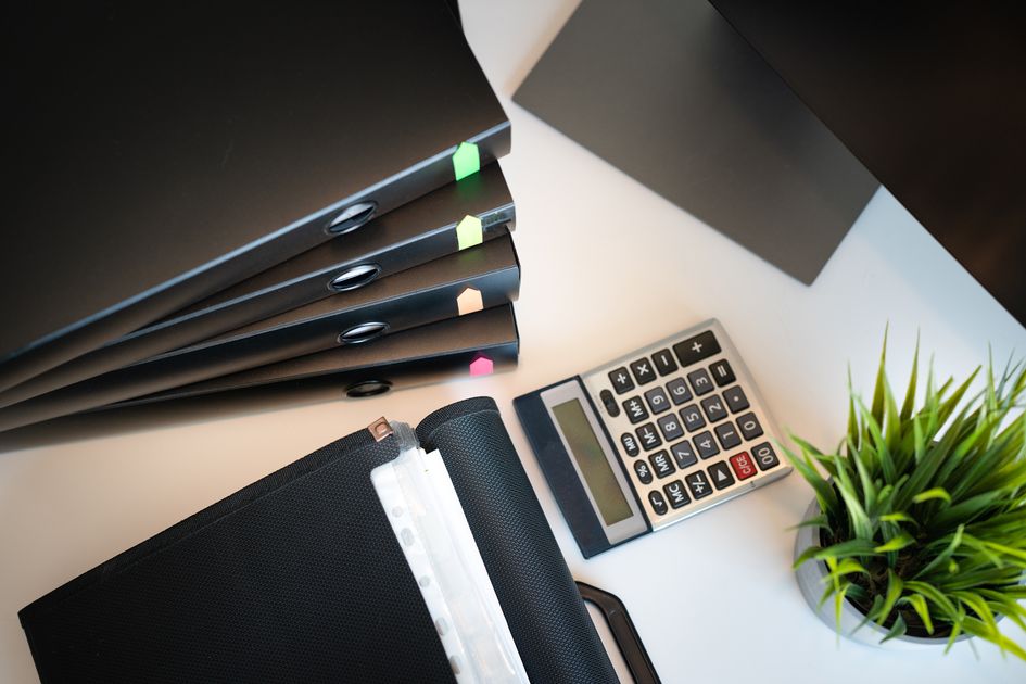 A tidy office desk with files and a calculator