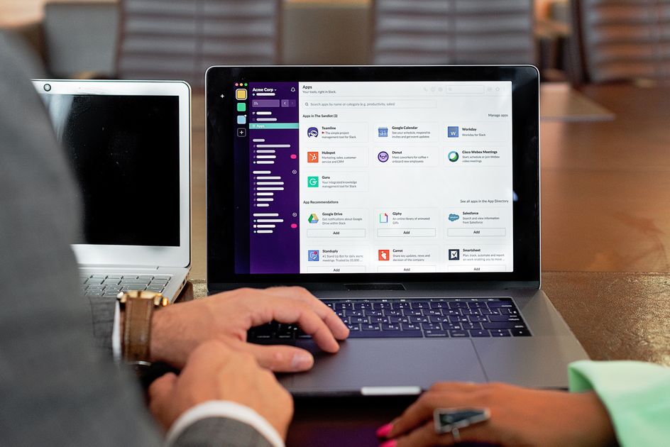 Two professionals collaborating with laptops and software