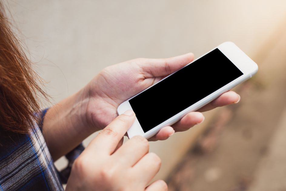 A person holding and using a smartphone outdoors