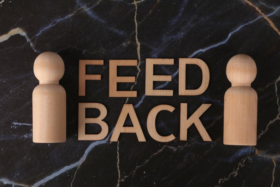 Wooden letters spelling feedback with figures on marble