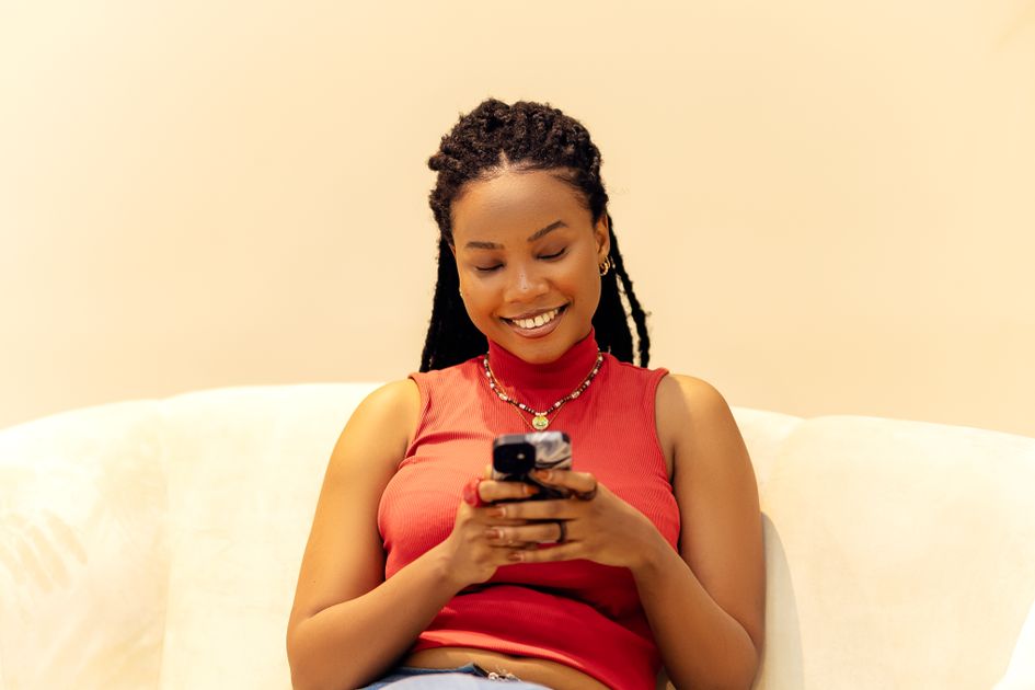 A woman smiling while using a smartphone indoors