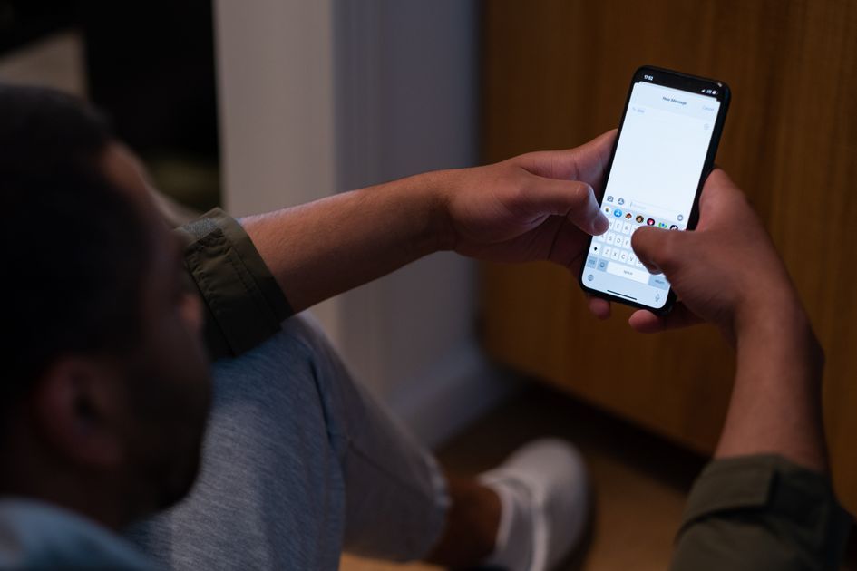A man texting on a smartphone indoors during the evening