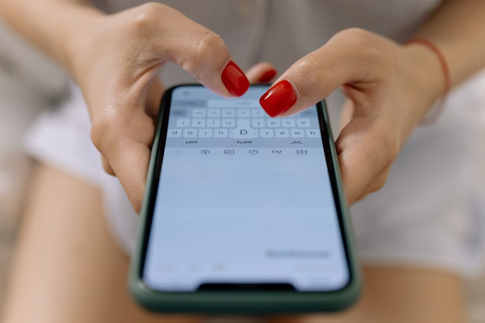 A close-up of hands typing on a smartphone screen