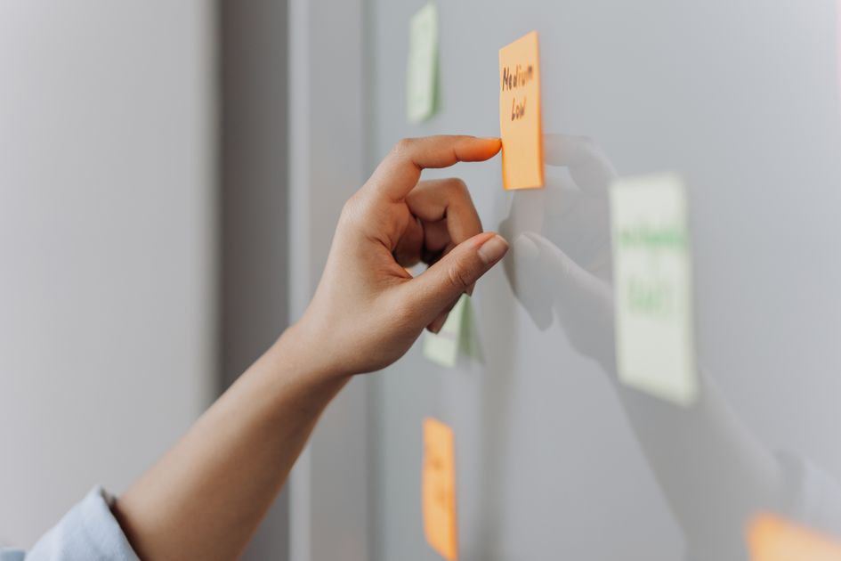 A hand placing a sticky note on a reflective surface
