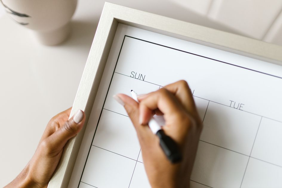 Hands holding a wall calendar, writing with a marker