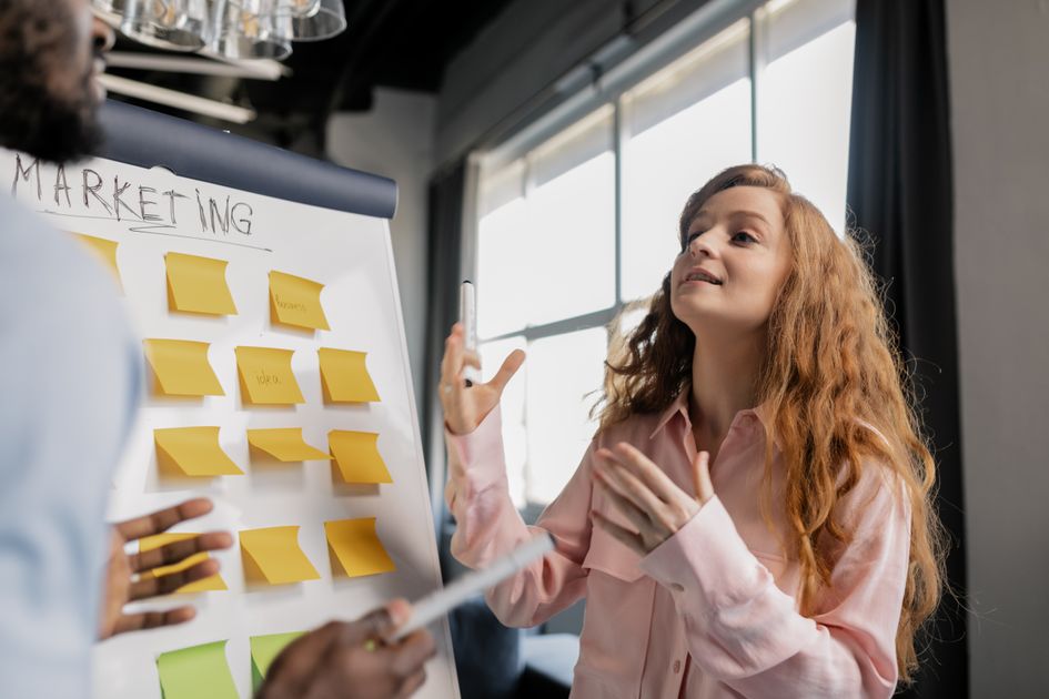 A woman discussing strategy using sticky notes on a board