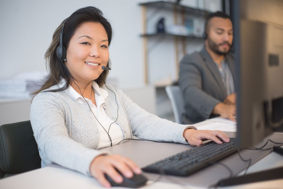 Two employees wearing headsets working together in an office