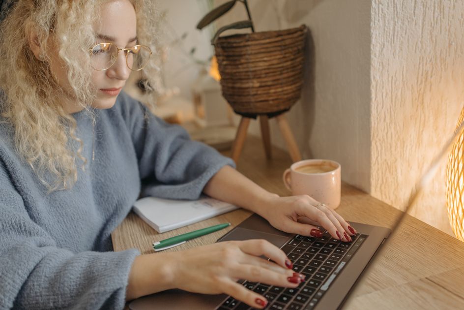 A curly-haired person wearing glasses using a laptop