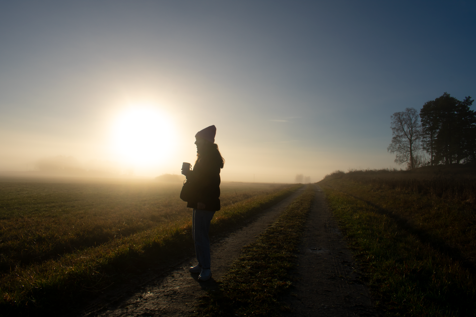 A silhouette relaxing at dawn by the water