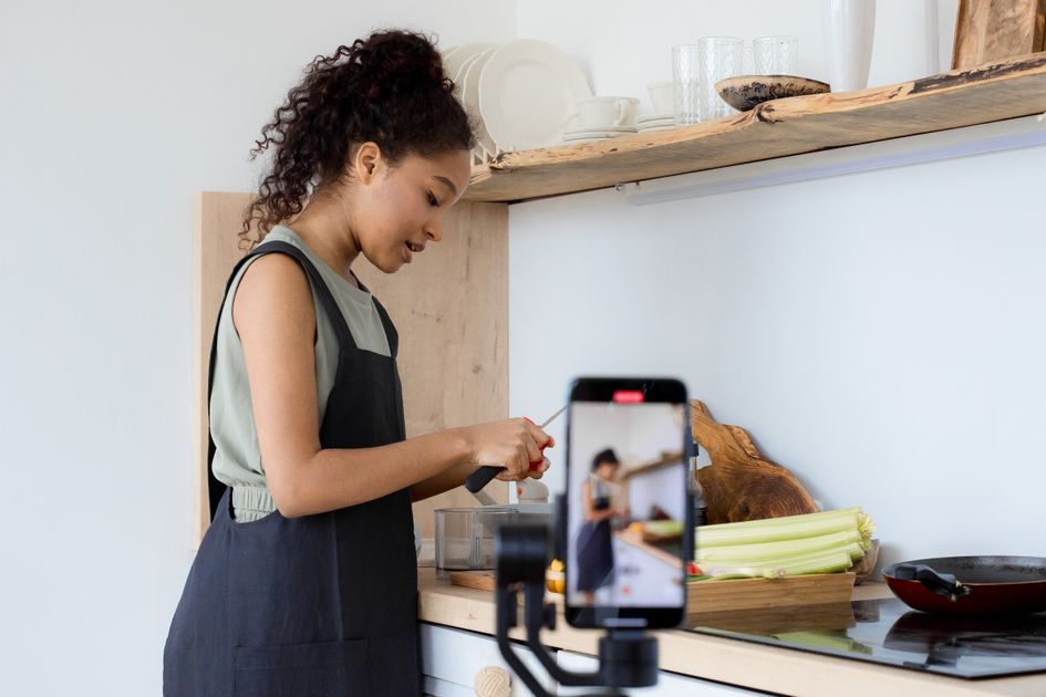 A woman filming cooking content in a modern kitchen