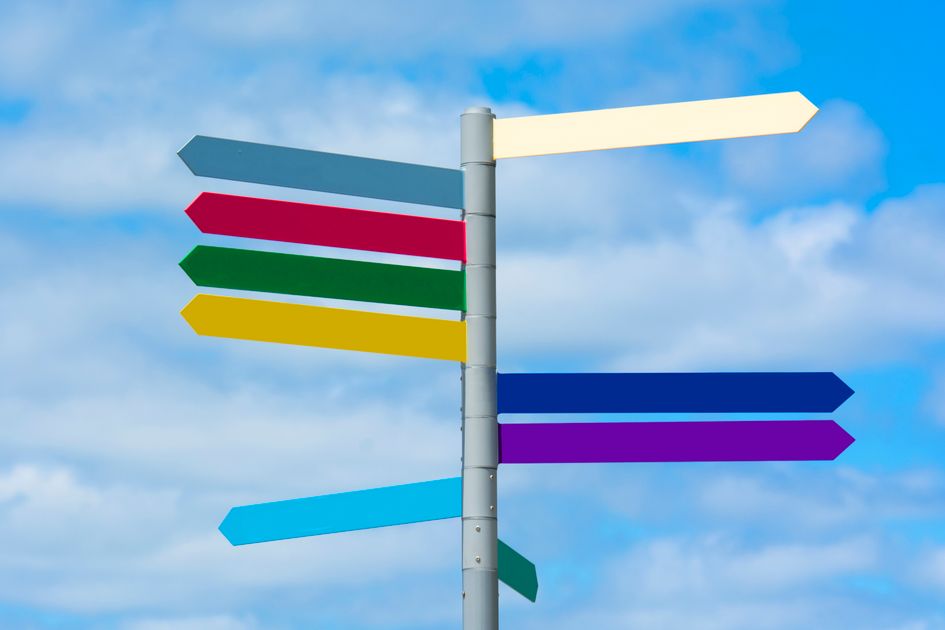 A colorful directional signpost against a vibrant blue sky