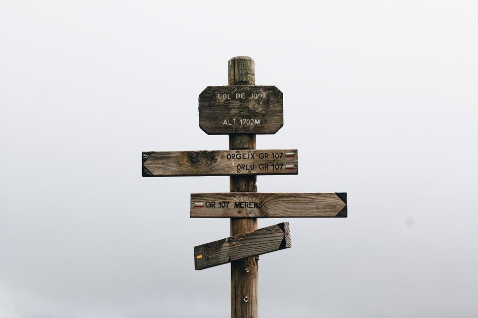 A vintage wooden signpost in a foggy mountain landscape