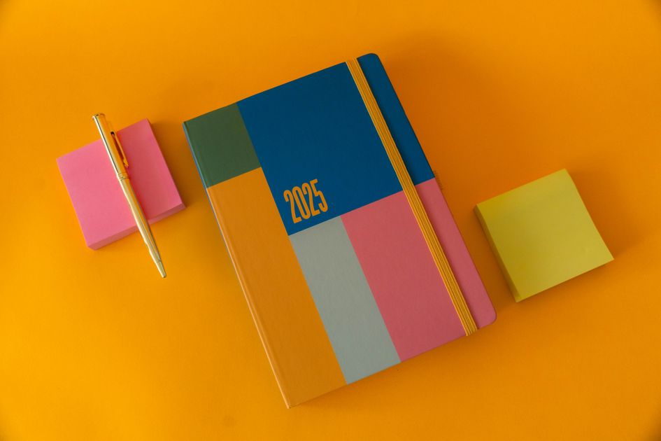 A colorful planner with sticky notes and a pen