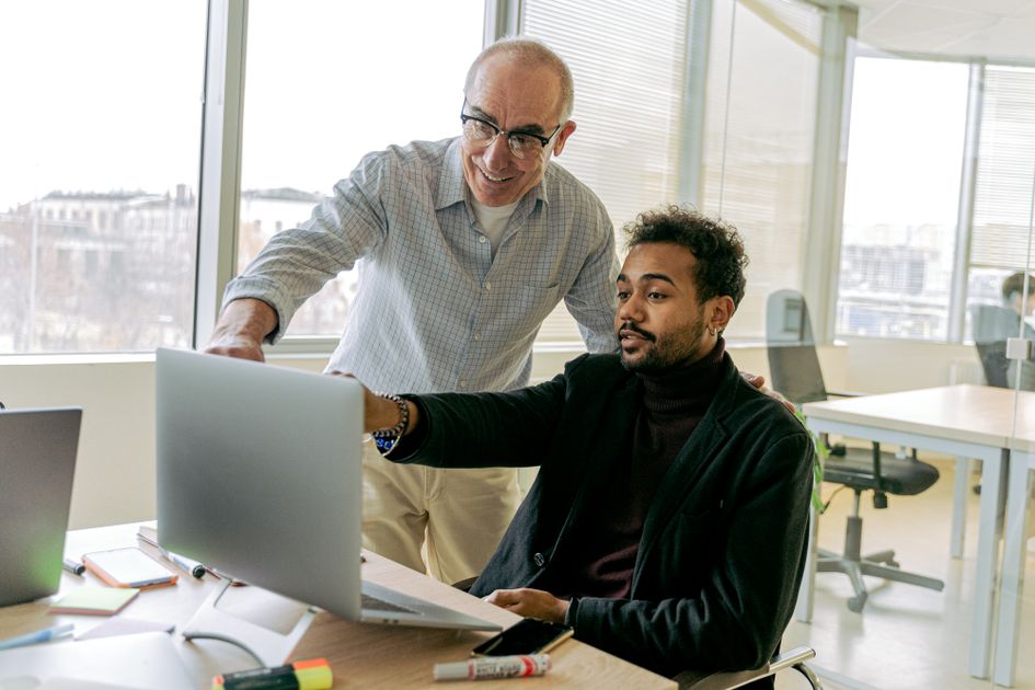 Colleagues collaborating in a bright office, focusing on a laptop