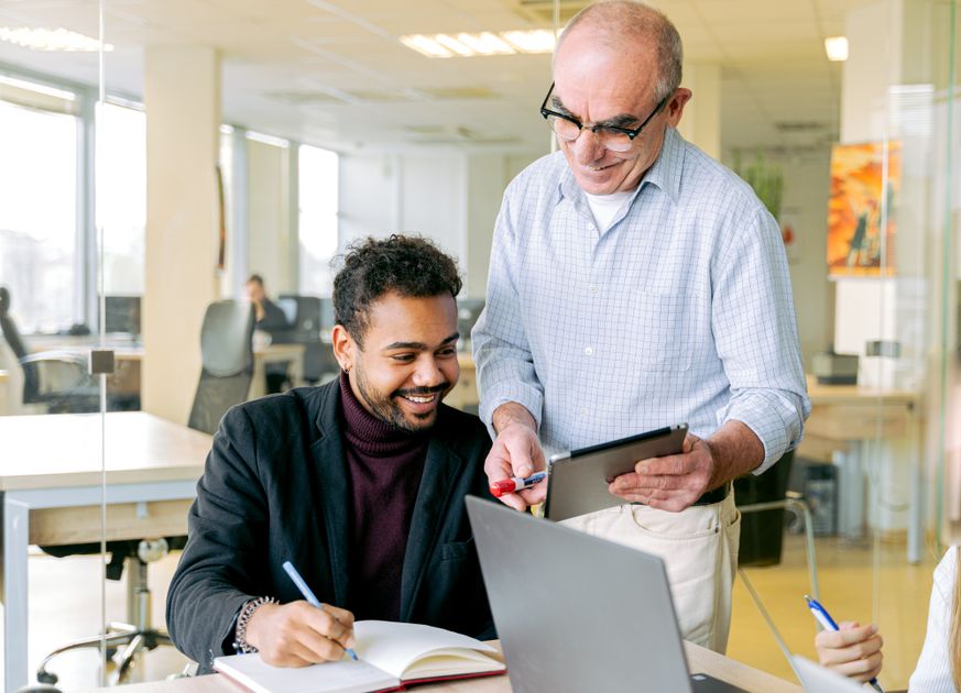 Two colleagues in discussion using digital devices and notes