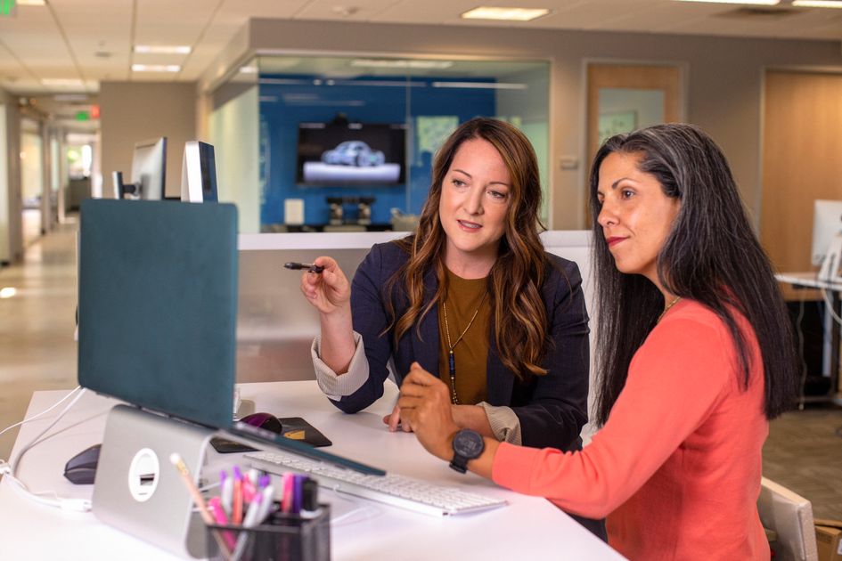 Two professional women discussing project details together