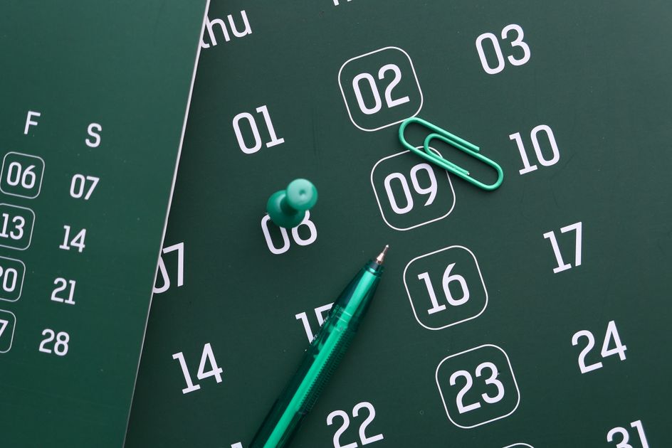 A green calendar with a pen and push pin