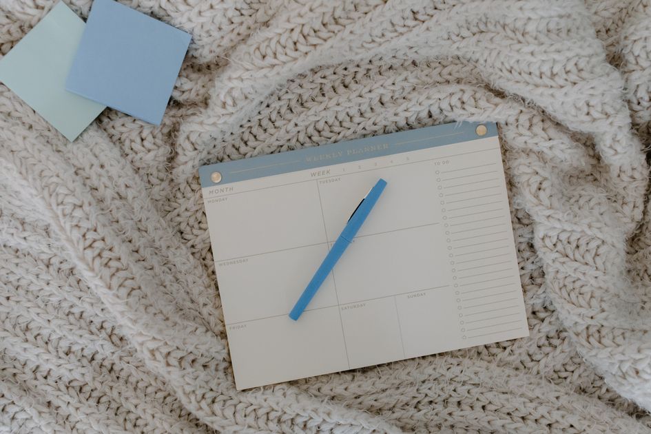 A weekly planner and pen on a cozy knitted blanket