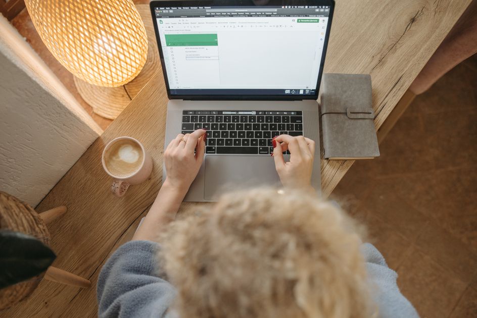 A person working on a laptop with coffee and a notebook