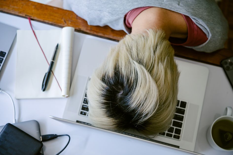 A tired woman resting her head on a laptop keyboard