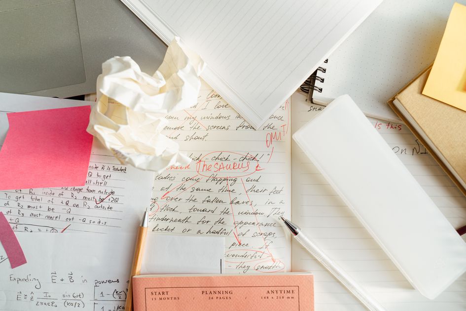 A cluttered desk with crumpled papers and notebooks