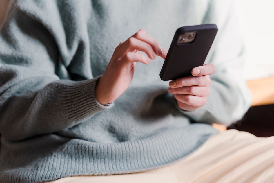A woman using a smartphone touchscreen while relaxing at home