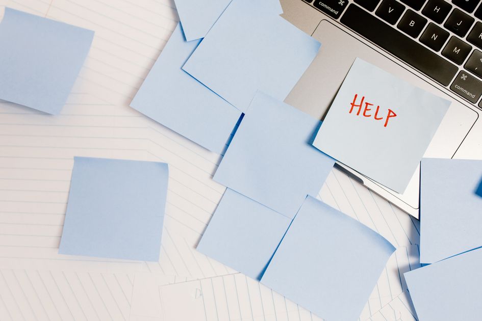 A cluttered workspace with sticky notes on a laptop