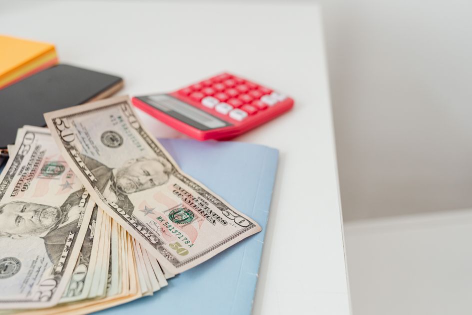 Notebooks, US dollars, and a calculator on a desk