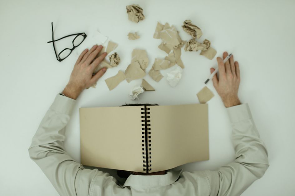 An exhausted person resting among crumpled papers