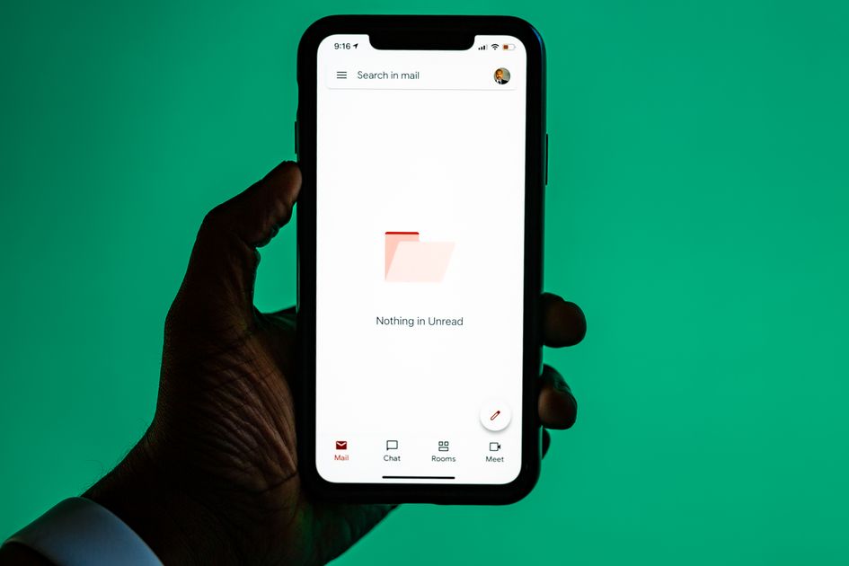 A hand holding a smartphone displaying an email app
