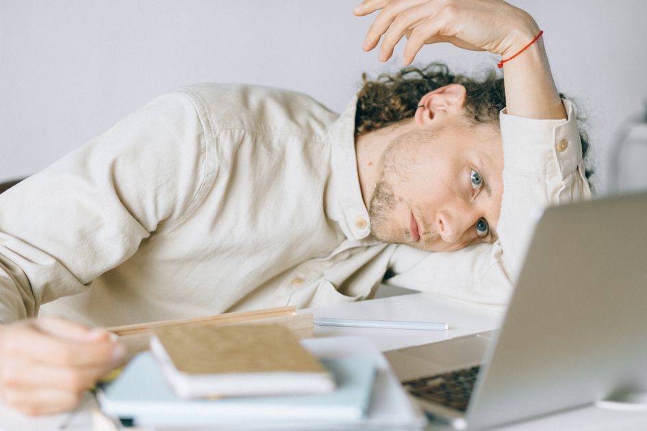 A tired person at a desk showing signs of exhaustion