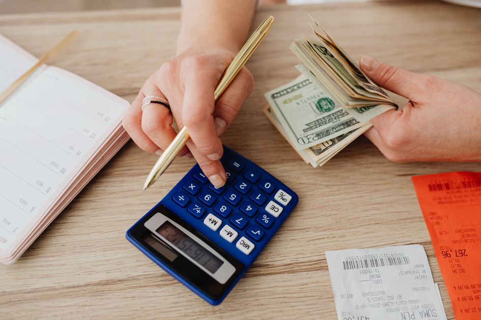 Hands handling cash and a calculator for budget planning