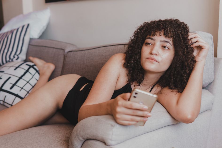 A young woman relaxing on a sofa while browsing her smartphone