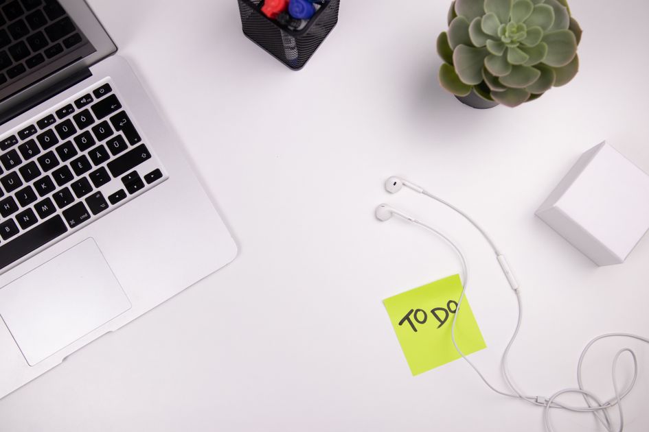 A to-do list note lying on a desk next to a laptop