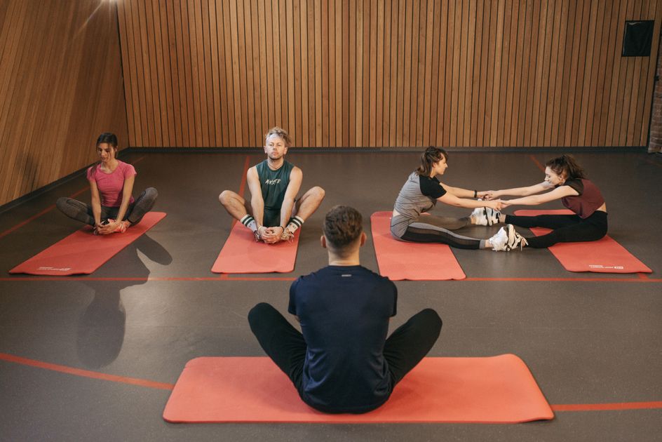 A group taking part in a yoga class on red mats