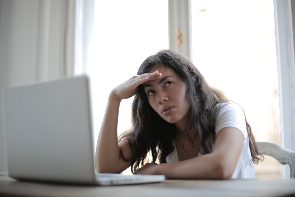 An entrepreneur touching her head while working at a laptop