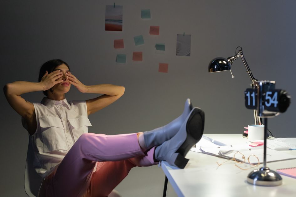 An overworked woman taking a break at her desk, showing exhaustion