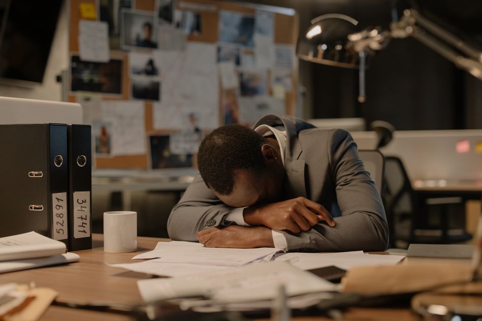 A stressed businessman overwhelmed by paperwork in an office