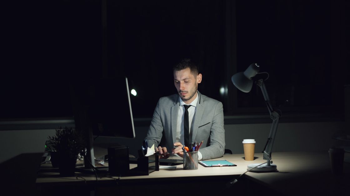 A businessman working late in a dimly lit office at night