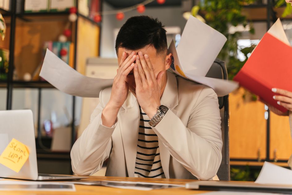 An Asian businesswoman with a headache at her desk, displaying stress