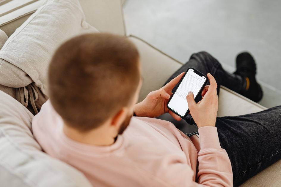 A man sitting on a sofa engaged with a smartphone