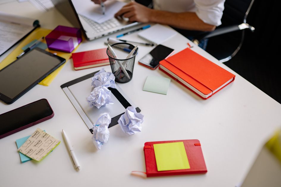 A cluttered office desk with notebooks and papers