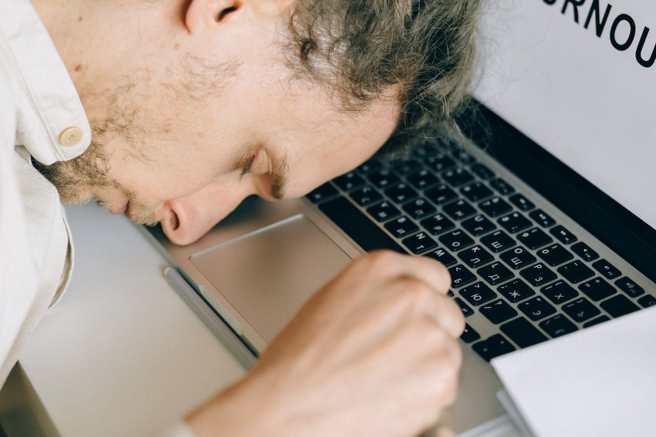 An exhausted employee resting their head on a laptop keyboard