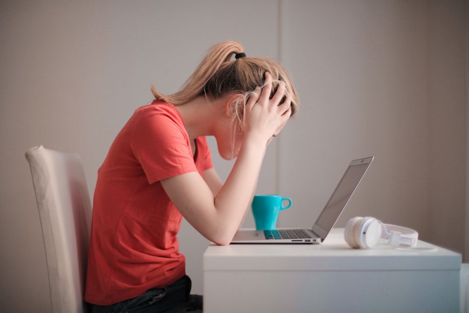 A young woman feeling stressed while studying at home with a laptop