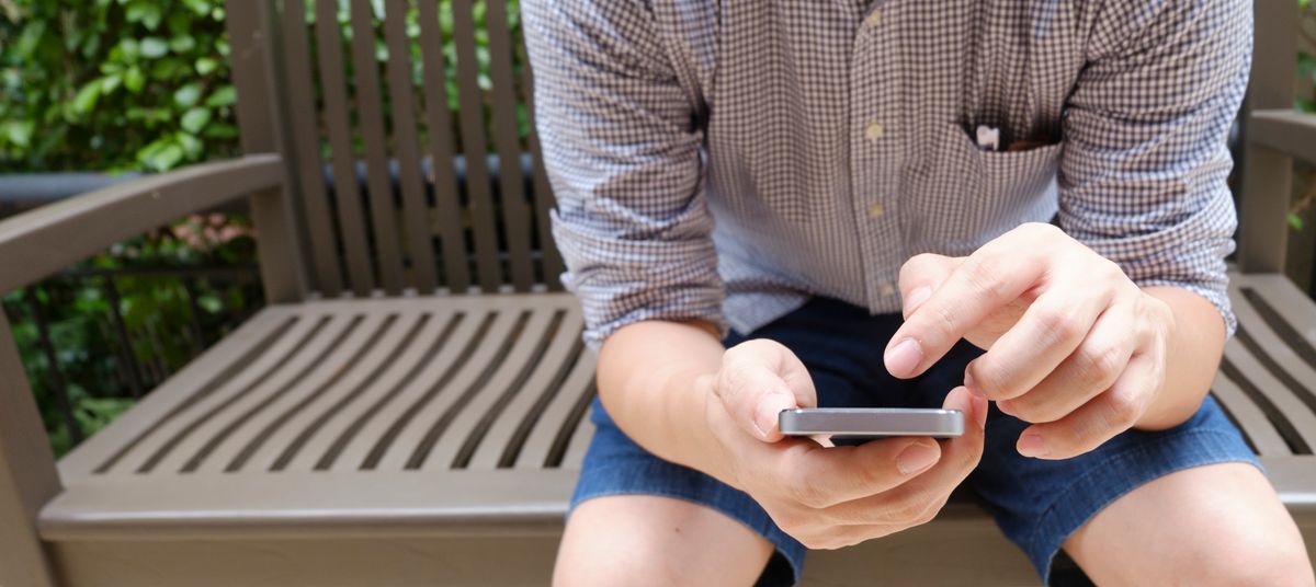 A man sitting on a bench using a smartphone